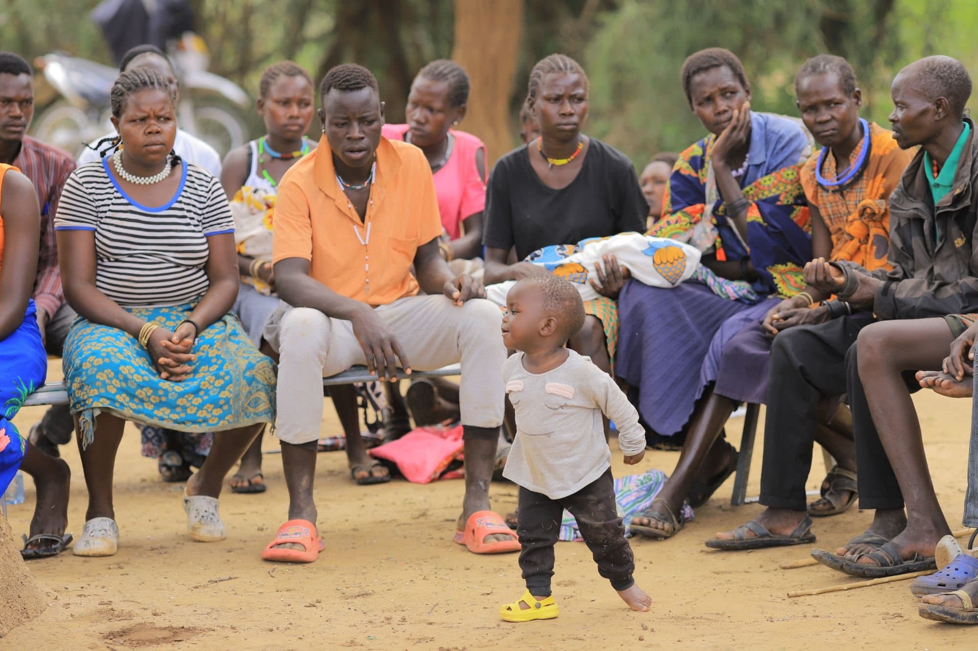Community members gathered for a neighbourhood meeting, with a young child in the foreground