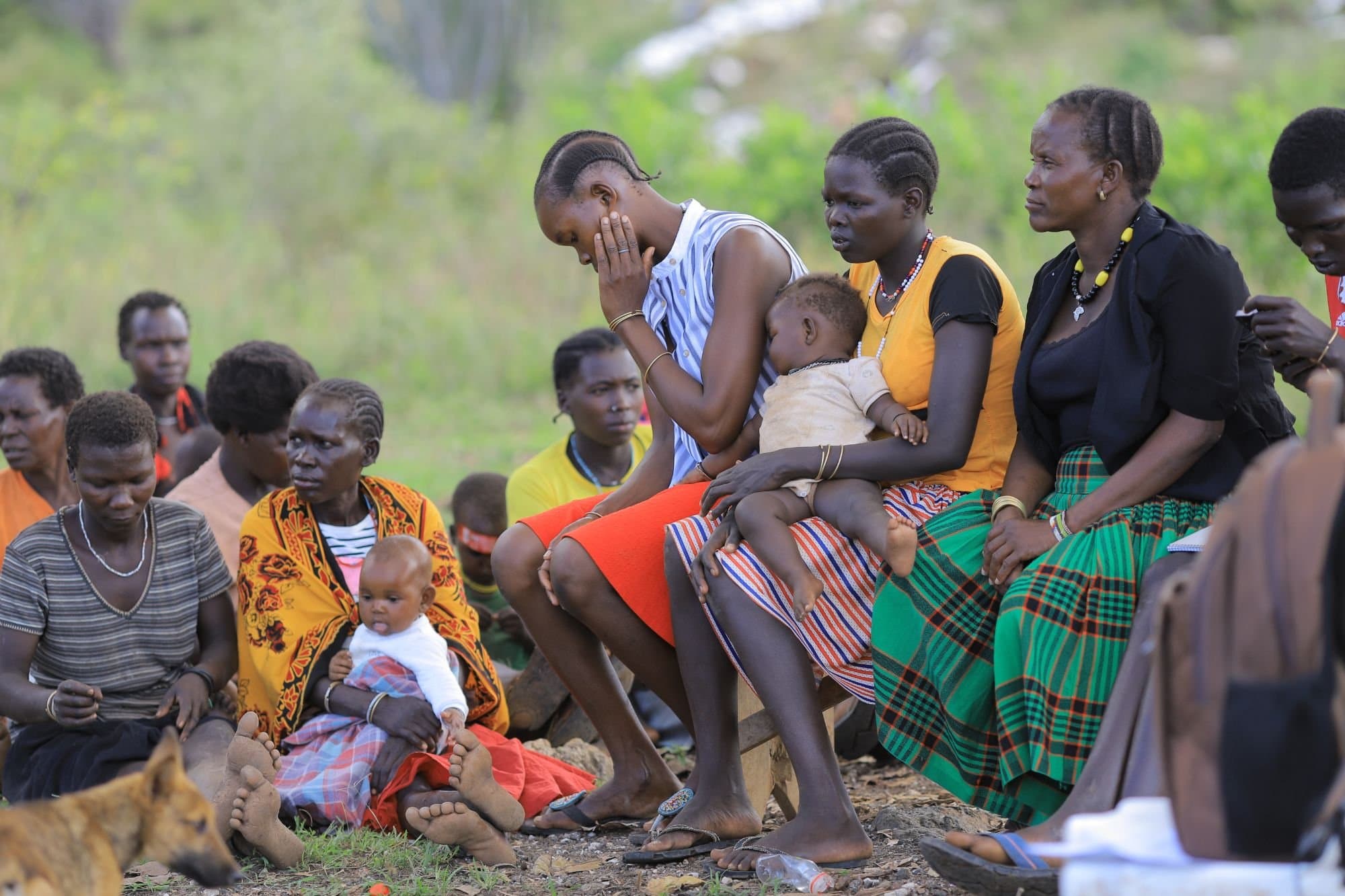 A caregiver holding and comforting a young child among a group of women